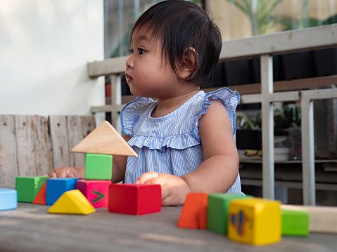 Little asian girl playing with wood blocks on the floor